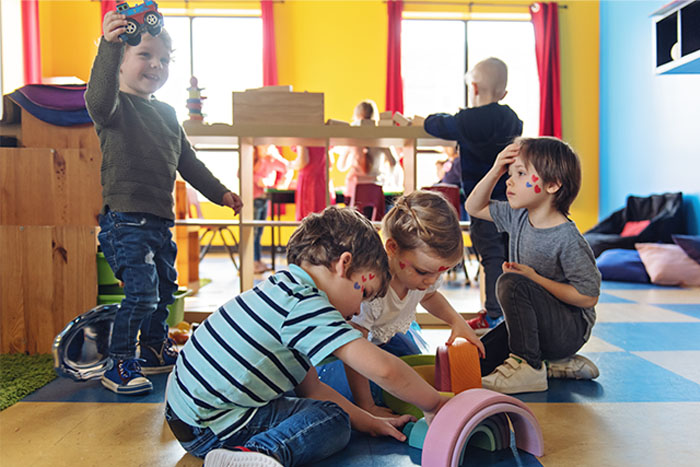 Mehrere Kinder spielen gemeinsam mit buntem Spielzeug in einer Kita: typische Eingewöhnungs-Situation für ein Kind mit schwerer Hämophilie A.